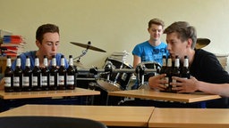 Zwei Jungs machen Musik auf Bierflaschen.  